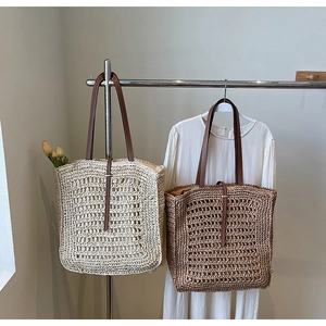 Detailed close-up of large woven straw tote bags in cream and brown with leather straps