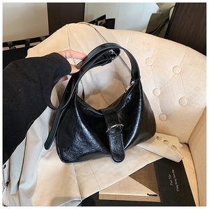 Detail shot of the black glossy leather hobo bag with a silver metal buckle closure