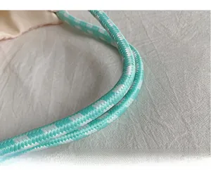 Gros plan sur la bandoulière en corde tressée bleu clair et blanc d'un sac cabas