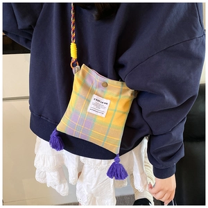 Detail of plaid crossbody bag with purple fringe and colorful woven shoulder strap