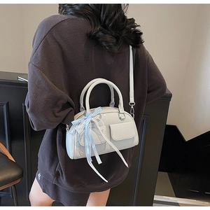 Detail of light blue glossy leather boston bag with ribbon handle and small front pockets
