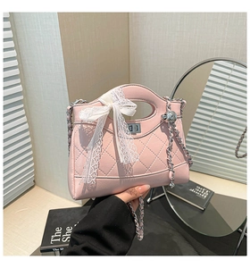 Detail of pink quilted bucket bag with lace bow, chain strap and metallic ball charm