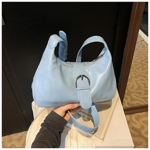 Detail of light blue glossy leather hobo bag with silver buckle and adjustable strap