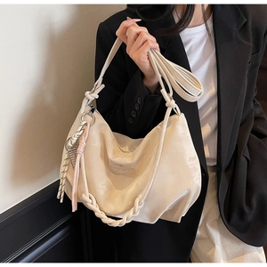 Close-up of beige hobo bag showing woven knot handle and textured nylon fabric details