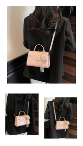 Detail view of pink square crossbody bag with mini plush bear charm and reinforced handle