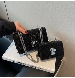 Detail of black snake-textured crossbody bags with silver locks in two sizes