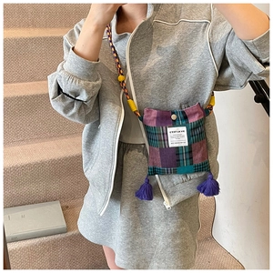 Detailed shot of retro plaid patchwork crossbody bag with purple tassels and woven strap