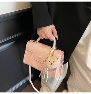 Detail of pink PU leather small square handbag with fold texture and plush bear charm