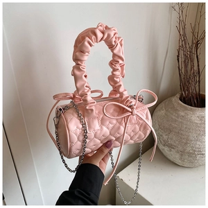 Détail du sac Boston rose matelassé avec poignée froissée et ornements de nœuds