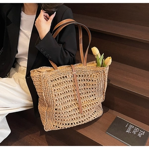Close-up of the large straw tote bag with brown leather straps and woven texture details