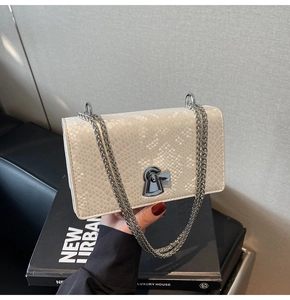 Detail of white snake skin texture on chain crossbody bag with silver keyhole lock