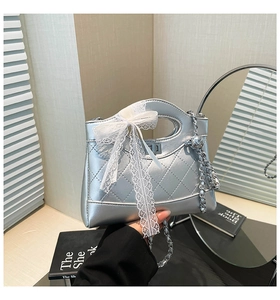 Detail view of a silver quilted bucket bag featuring a lace bow and chain strap