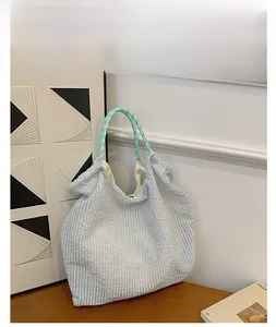 Gros plan du sac cabas plissé à rayures avec des anses à damier sur une surface en bois