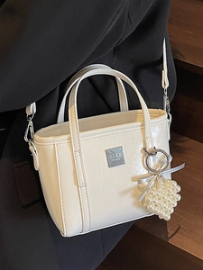 Borsa a secchiello minimalista in pelle beige con ciondolo di perle e logo ZSKE PARIS