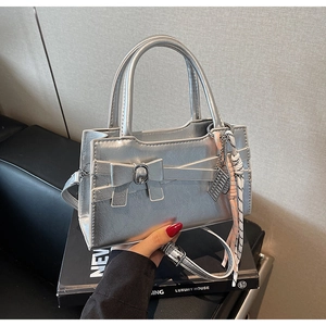 Dettaglio della borsa metallica argento con fiocco e ciondolo abaco decorativo