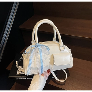 Detail of white Boston bag featuring silk scarf bow and silver hardware on stairs