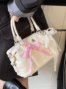 White leather Boston bag with pink plaid bow and embossed paw prints held by model