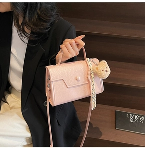 Pink PU leather crossbody bag featuring unique pleated texture and a cute plush bear charm