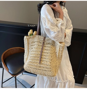Macro detail of natural straw tote bag featuring brown leather straps and hollow weave