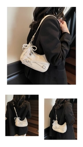 Detail of white patent leather crescent bag with pearl bow and silver heart charm