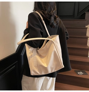 Detail of soft beige leather tote bag featuring a decorative lace bow on the side