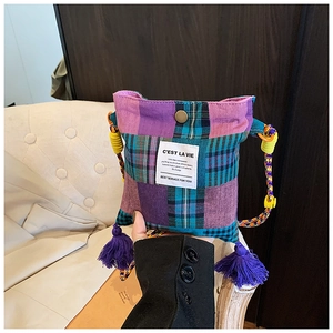 Detail of vintage plaid crossbody bag with purple tassels and woven shoulder strap