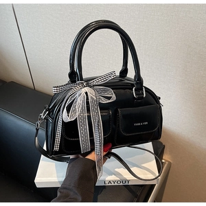 Detail of black glossy leather Boston bag featuring checkered bow and mesh decoration