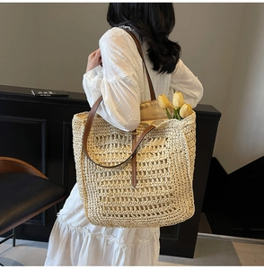 Detailed macro view of large woven straw tote bag with brown leather straps and tulip decor