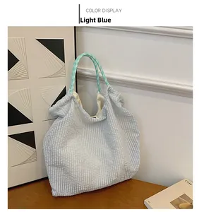 Détail du sac cabas en toile plissée bleu clair avec anses en corde tressée verte sur bois