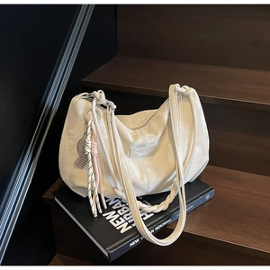 Detailed macro view of cream hobo bag showing zipper closure and colorful woven charm