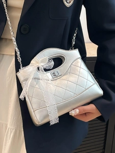 French luxury silver quilted bucket bag with lace bow and metal chain strap on model
