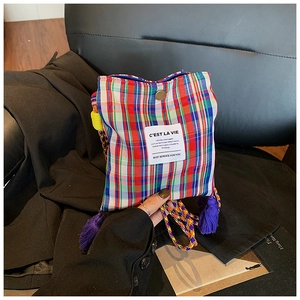 Detail of colorful plaid mini crossbody bag with purple fringe and braided strap