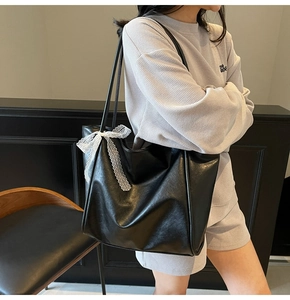 Detail view of black leather tote bag with white lace bow on grey waffle lounge outfit