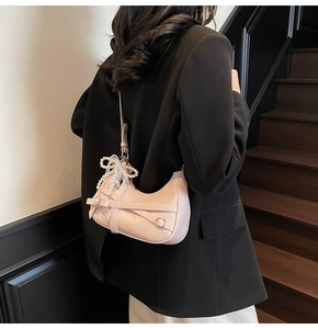 Detail of light pink hobo bag with bow tie design and decorative pearl chain