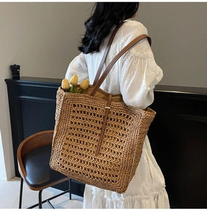 Detail of handwoven straw tote bag with brown leather straps and floral accent detail
