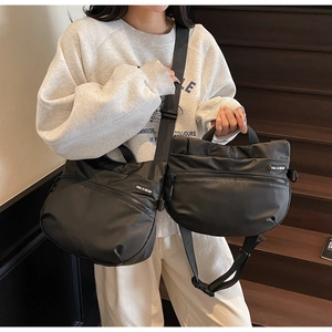 Detail of black crescent crossbody tote bag with adjustable strap and front zipper pocket