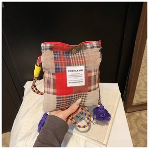 Close-up of retro plaid patchwork crossbody bag with tassel and woven rope strap