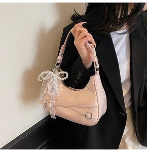 Pink crescent underarm bag featuring delicate lace bow, pearls, and crisscross strap detail