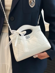 White quilted patent leather bucket bag with silver chain and lace bow on a model