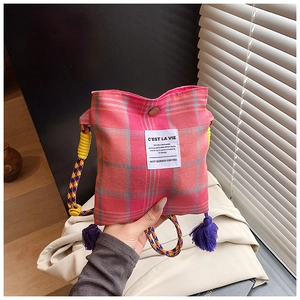 Close-up of pink plaid canvas bag featuring colorful woven strap and purple tassel charm