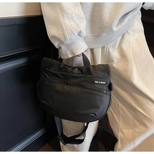 Detail of black sporty tote bag showing adjustable strap and multi-layer zippers
