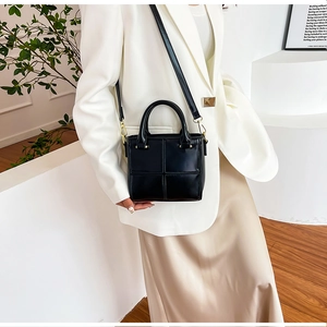 Sac à main noir matelassé avec garniture dorée porté par un mannequin en décor