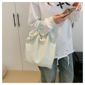 Détail du sac cabas plissé vert clair avec fermeture à bouton-pression en résine