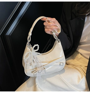 Detail of white hobo bag with lace trim, ribbon criss-cross and pearl bow charm