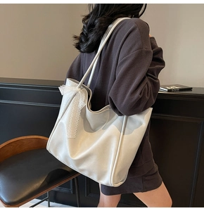 Detail view of large white faux leather tote bag with lace bow decoration on model