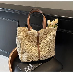 Detailed macro view of woven straw tote bag texture and brown leather strap detail