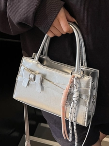Piccola borsa a mano squadrata argento metallizzato con fiocco e ciondolo tessuto