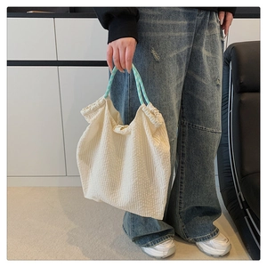 Détail du sac cabas en seersucker avec anses à carreaux bleus et tissu plissé texturé