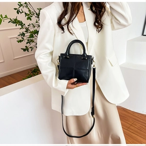 Sac seau matelassé noir chic avec détails dorés et poignées porté par un mannequin