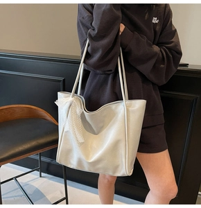 Detailed side view of off-white faux leather tote bag with lace bow decoration